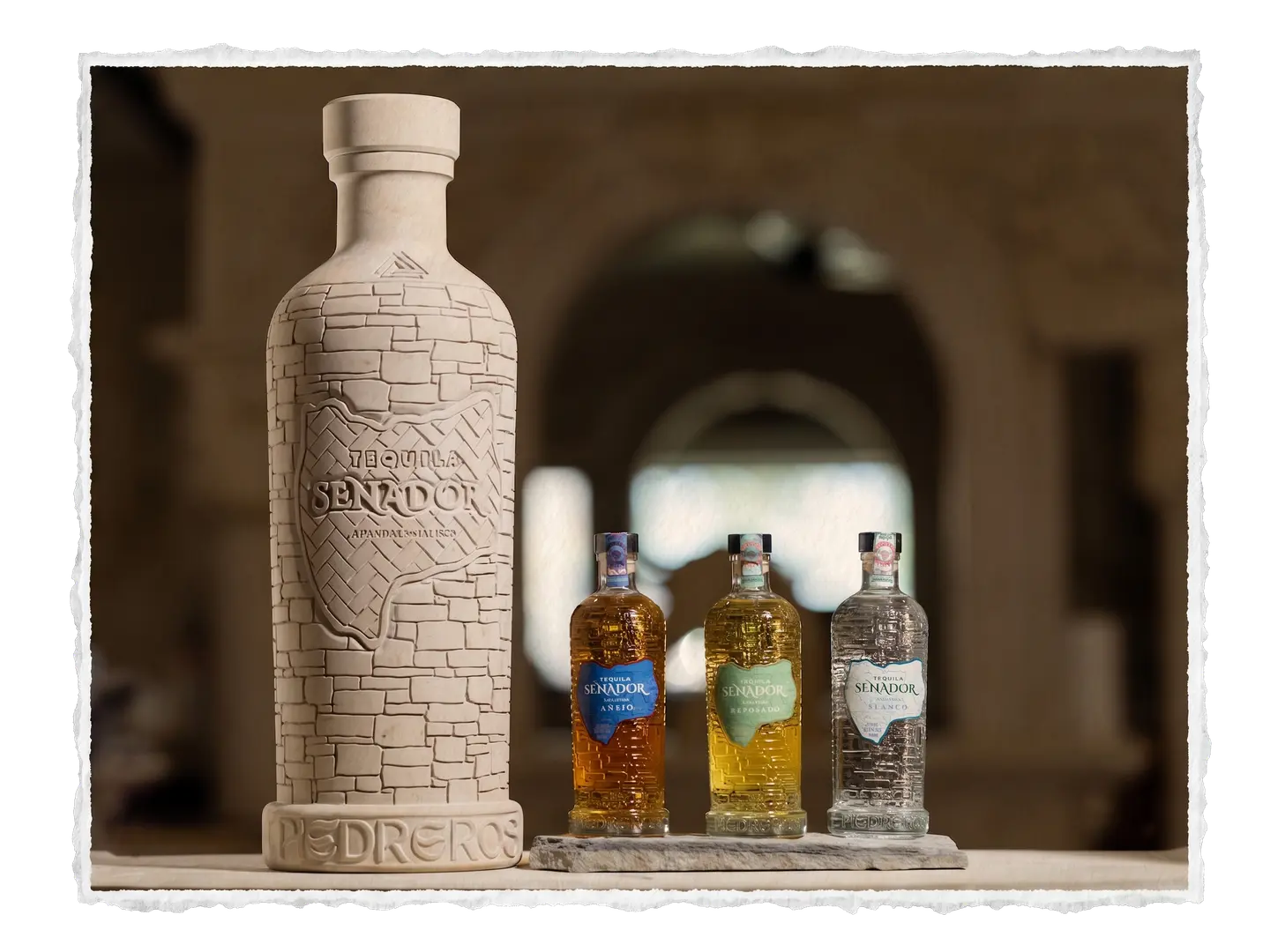 Carved Piedreros stone bottle beside Senador tequila bottles in the workshop
